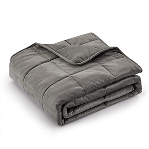 May include: A folded, gray weighted blanket. The blanket is made of a soft, plush material and is divided into square sections. The blanket is designed to provide a sense of calm and relaxation. The blanket is folded neatly.