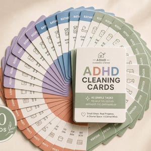 May include: A deck of 40 ADHD Cleaning Cards arranged in a fan shape. The top card features the text ADHD CLEANING CARDS, 40 SIMPLE TASKS TO HELP YOU CLEAN WITHOUT THE OVERWHELM, and Small Steps. Real Progress. A Cleaner Space. A Calmer Mind.