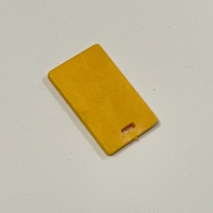 May include: A small, yellow plastic cutting board with a small hole in the center.