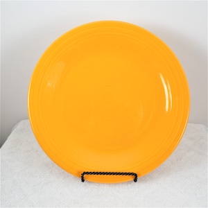 Pu&ograve; includere: Un piatto da cena in ceramica giallo brillante con un bordo leggermente ondulato.