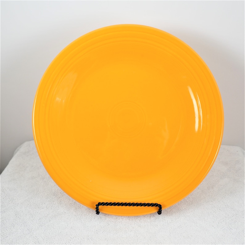 Pu&ograve; includere: Un piatto da cena in ceramica giallo brillante con un bordo leggermente ondulato.