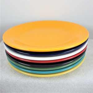 Pu&ograve; includere: Un set di otto piatti da cena in ceramica colorati. I piatti sono in tonalit&agrave; di giallo, blu, bianco, rosso, verde e turchese.
