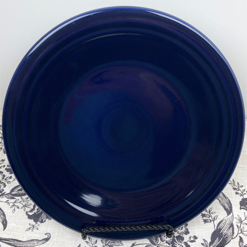May include: A deep blue ceramic dinner plate with a slightly raised rim.