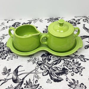 May include: A green ceramic creamer and sugar bowl set with a matching tray. The set is in a bright, lime green color.