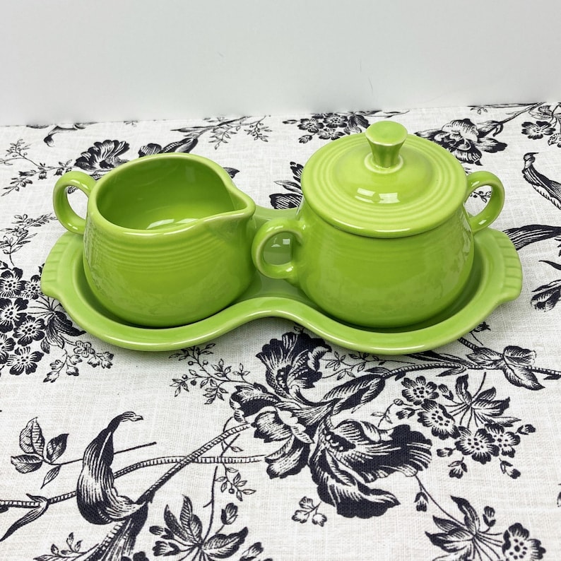 May include: A green ceramic creamer and sugar bowl set with a matching tray. The set is in a bright, lime green color.