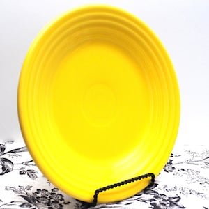 May include: A bright yellow ceramic dinner plate with a slightly raised rim and a smooth, glossy finish.