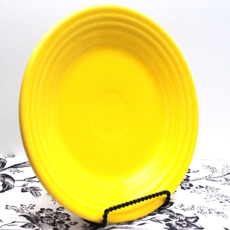 May include: A bright yellow ceramic dinner plate with a slightly raised rim and a smooth, glossy finish.