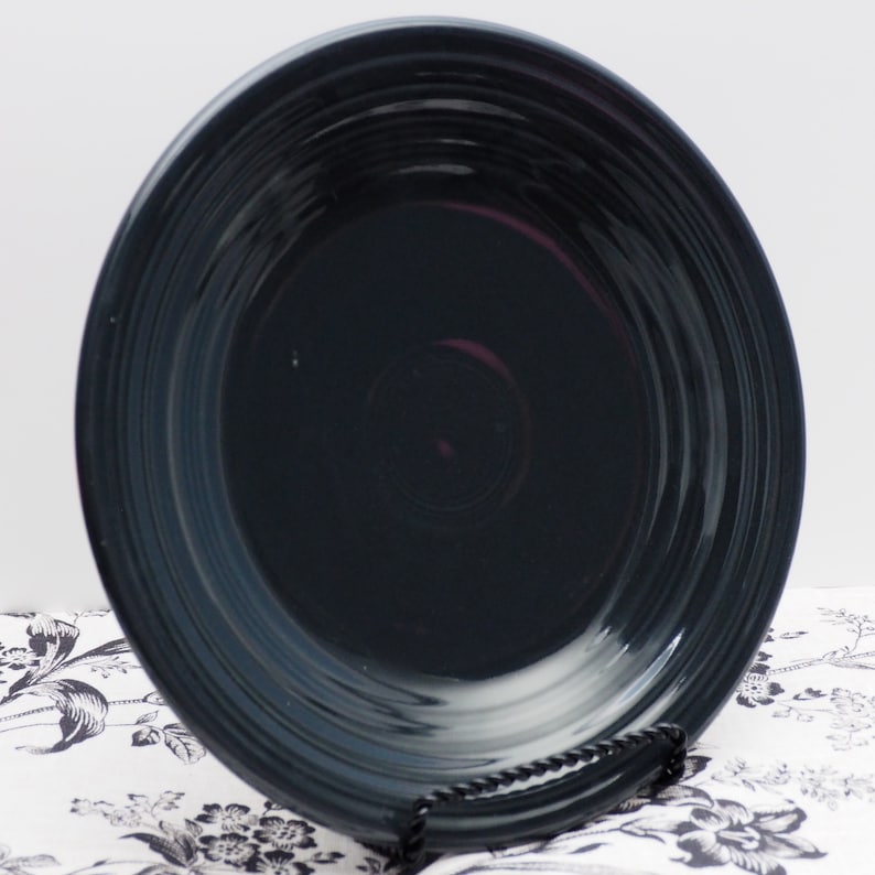 May include: A dark blue ceramic dinner plate with a rippled design. The plate is made by Fiesta and is a popular choice for everyday dining.