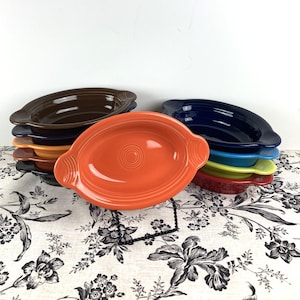 May include: A set of eight oval ceramic baking dishes with handles. The dishes are in various colors, including brown, blue, orange, yellow, and red.