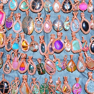 May include: A collection of wire-wrapped pendants featuring various natural stones and crystals. The pendants are made with copper wire and feature a variety of colours and patterns.