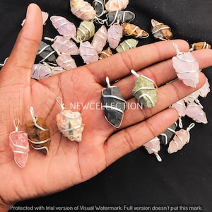 以下が含まれることがあります： 手の中に、ワイヤーで巻かれたクリスタルペンダントがいくつかあります。ペンダントは、ローズクォーツ、アメジスト、タイガーアイなど、さまざまな種類のクリスタルで作られています。ワイヤーは銀色で、クリスタルに螺旋状に巻かれています。ペンダントの長さはすべて約2.5〜5cmです。