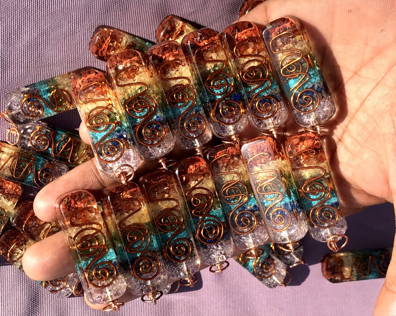 Pu&ograve; includere: Primo piano di un mucchio di bacchette di cristallo dei sette chakra con filo di rame avvolto attorno. Le bacchette sono in quarzo trasparente con cristalli di diversi colori incastonati, che rappresentano i sette chakra. Le bacchette sono lunghe circa 5 cm.