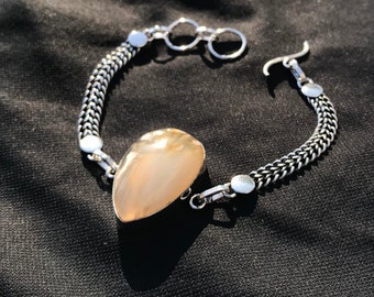 May include: A silver chain bracelet with a large, teardrop-shaped, light brown agate stone pendant.