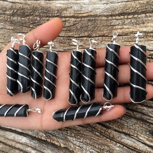 Puede incluir: Una colecci&oacute;n de colgantes de obsidiana negra envueltos en alambre de plata. Los colgantes tienen diferentes longitudes y formas. Son perfectos para hacer joyas o usar en manualidades.