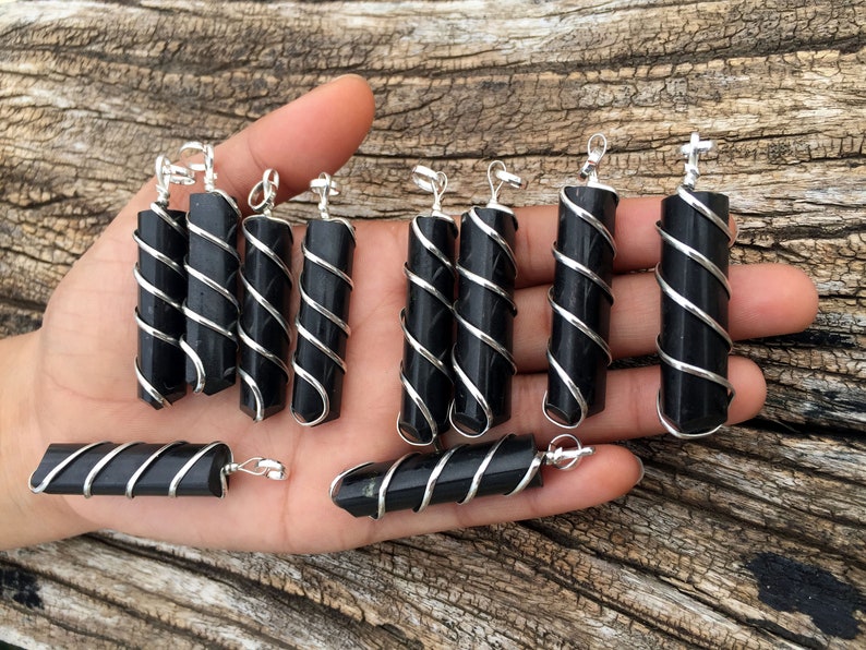 Puede incluir: Una colecci&oacute;n de colgantes de obsidiana negra envueltos en alambre de plata. Los colgantes tienen diferentes longitudes y formas. Son perfectos para hacer joyas o usar en manualidades.