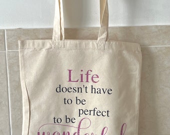 May include: A white canvas tote bag with pink glitter lettering that reads "Life doesn't have to be perfect to be wonderful".