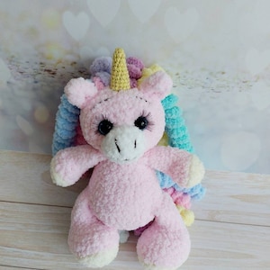 Plush pink unicorn with multi-colored curls. A great gift for a girl. A plush rainbow unicorn friend