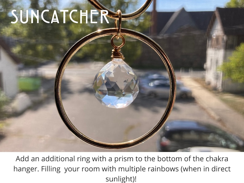 K&ouml;nnte beinhalten: Ein goldener Sonnenf&auml;nger mit einem Kristallprisma, das an einem Ring h&auml;ngt. Der Sonnenf&auml;nger ist so konzipiert, dass er Regenb&ouml;gen erzeugt, wenn Sonnenlicht durch ihn scheint. Der Text "SUNCATCHER" ist oben im Bild sichtbar.