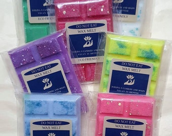 May include: Assortment of colorful wax melt bars in clear packaging. Each bar is a different color, including green, white, pink, purple, yellow, blue, and pink. Each package has a label that reads "DO NOT EAT" and "WAX MELT".