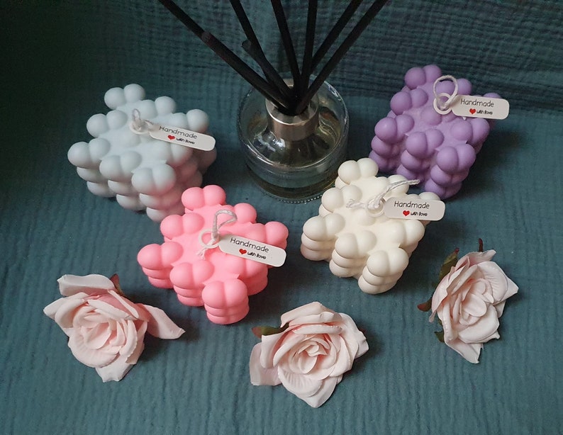 May include: Four handmade bubble candles in different colors: light blue, pink, white, and purple. Each candle has a small tag that says "Handmade with love".
