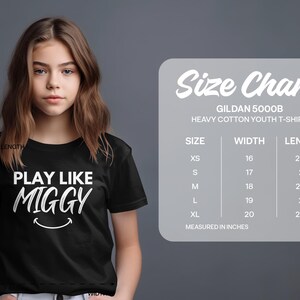 May include: Black youth t-shirt with white text that reads "Play Like Miggy" and a smiley face. Size chart for Gildan 5000B Heavy Cotton Youth T-Shirt with measurements in inches.