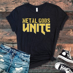 Puede incluir: Una camiseta negra con las palabras "Metal Gods Unite" en letras amarillas.