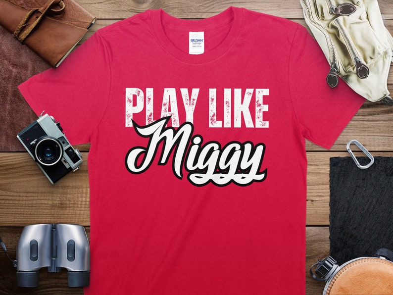 May include: Red t-shirt with white text that reads "Play Like Miggy".