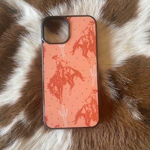 May include: A pink phone case with a cowboy riding a horse and cactus pattern.