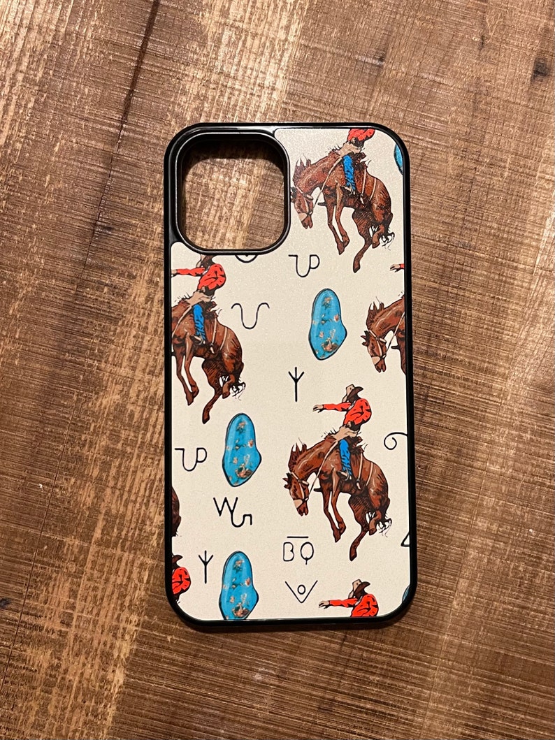 May include: A white phone case with a black border and a pattern of cowboys riding horses and turquoise stones. The case has the letters "BQ" and other symbols on it.