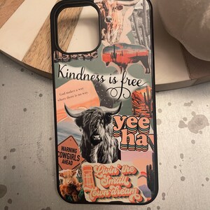 May include: A black phone case with a collage of images and text. The images include a cow, a sunset, a cactus, and a highland cow. The text includes "Kindness is free", "God makes a way where there is no way", "Warning Cowgirls Ahead", "Yee Haw", and "Livin' the Small Town Dream".