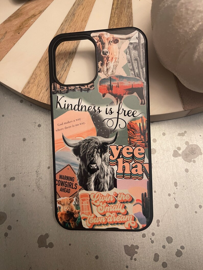 May include: A black phone case with a collage of images and text. The images include a cow, a sunset, a cactus, and a highland cow. The text includes "Kindness is free", "God makes a way where there is no way", "Warning Cowgirls Ahead", "Yee Haw", and "Livin' the Small Town Dream".