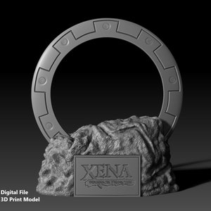 May include: A 3D-printed model of a circular object with a series of rectangular and circular cutouts, mounted on a textured, rocky base. The base features a rectangular plaque with the text "XENA WARRIOR PRINCESS".