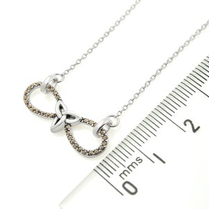 Infinity Necklace with Trinity Knot | Ireland Jewelry next to a scale in a white background