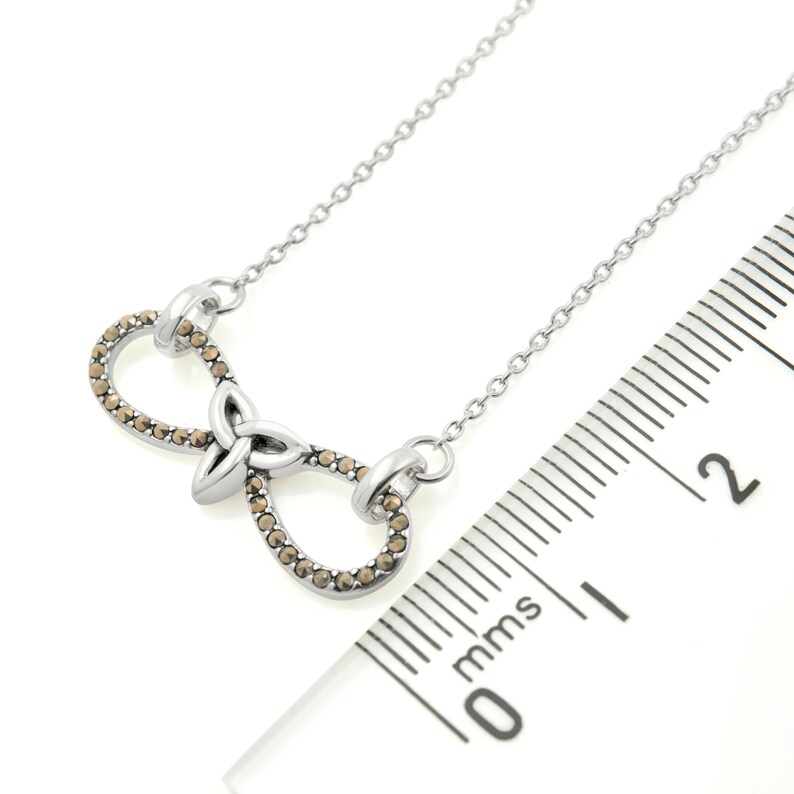Infinity Necklace with Trinity Knot | Ireland Jewelry next to a scale in a white background