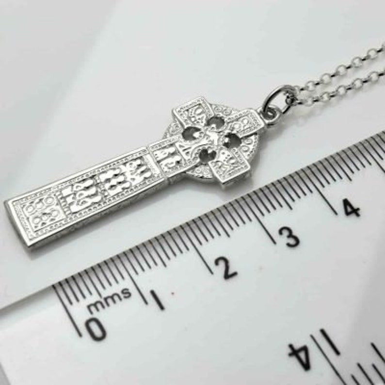 Silver Celtic Cross Necklace of Drumcliffe | Irish Replica Cross | Celtic Jewelry | placed next to a scale in a white background
