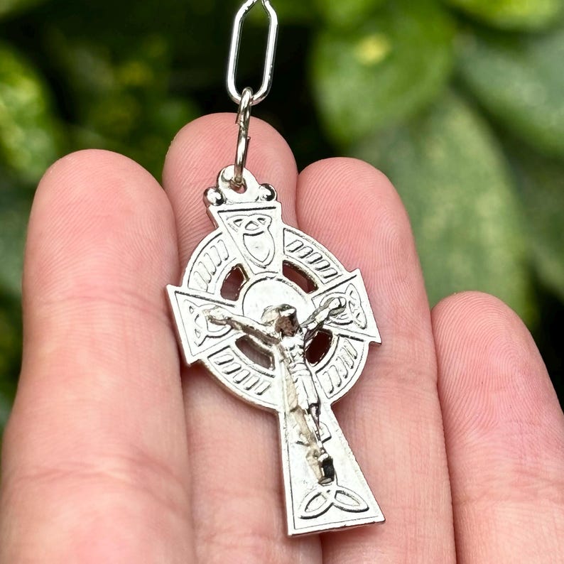 Pu&ograve; includere: Ciondolo a forma di croce celtica in argento con un design dettagliato e una figura di Ges&ugrave; Cristo sulla croce.