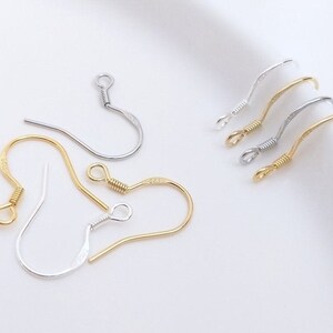 May include: A set of five earring hooks, two gold and three silver, with a loop at the top and a hook at the bottom. The hooks are made of metal and are designed for attaching earrings.