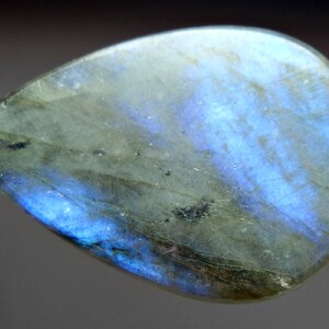 May include: A teardrop-shaped, iridescent labradorite gemstone with a blue and green color variation.