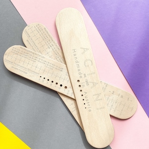 Puede incluir: Tres herramientas de medición de madera para tejer y hacer ganchillo. Las herramientas están etiquetadas como "AGIAN est. 1985 Hecho a mano en Austria". Las herramientas tienen marcas para diferentes tamaños en centímetros y pulgadas.