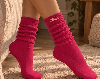 May include: A pair of vibrant fuchsia pink slouch socks featuring a textured cable knit pattern on the upper section. The left sock is personalized with the name Olivia embroidered in a white script font near the top ribbed cuff.
