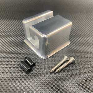 May include: A silver metal box with a rectangular shape and a small opening on one side. The box is accompanied by two black plastic caps and two silver screws.