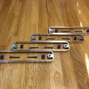 May include: Five silver metal frames with blue plastic screws and silver screws. The frames are arranged in a staggered pattern on a wooden surface.