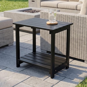 May include: A black rectangular side table with a slatted top and a lower slatted shelf. The table features four straight legs and a sturdy frame. A clear glass of water sits on a round wooden coaster placed on the center of the table surface.