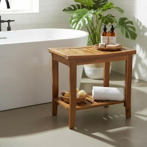 May include: A wooden bathroom bench with a slatted top and a lower shelf. The bench is made of light brown wood and has a rectangular shape. A white rolled towel and a basket with sponges are on the shelf. Two brown bottles and a tray are on top.