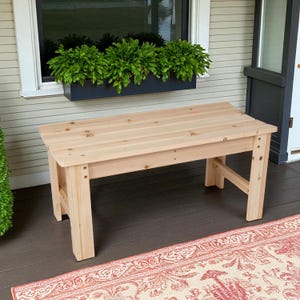 May include: A rectangular bench constructed from light-colored natural wood with a slatted top surface and four sturdy legs. The bench features visible wood grain patterns and is assembled with metal hardware visible on the side support beams.