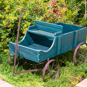 May include: A teal wooden wagon featuring a bench seat, a long metal handle for pulling, and four thin metal wheels. The wagon has a rectangular cargo area behind the seat and is constructed with horizontal wooden planks finished in a dark teal stain.