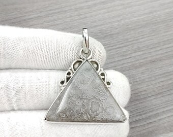 May include: A silver pendant with a triangular shaped gray and white agate stone. The pendant has a decorative silver bail.