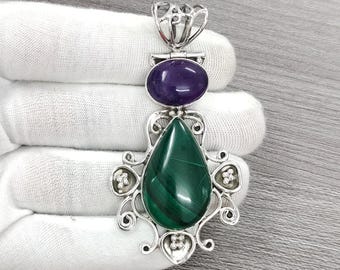 Pode incluir: Um pingente de prata com uma malaquita verde e uma ametista roxa. O pingente apresenta um design detalhado e ornamentado.