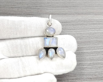 May include: A silver pendant with a geometric design featuring five moonstone stones. The stones are a milky white color and are set in a silver frame.