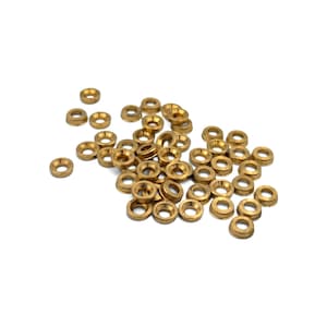 May include: A collection of small, circular brass washers with a metallic gold finish. Each washer features a raised, beveled edge and a central hole, designed for mechanical fastening or hardware applications. The pieces are scattered in a pile.